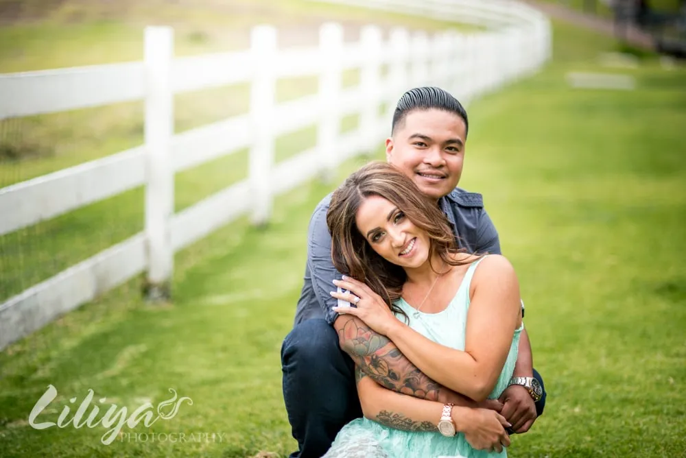 Couple embracing beside a white fence