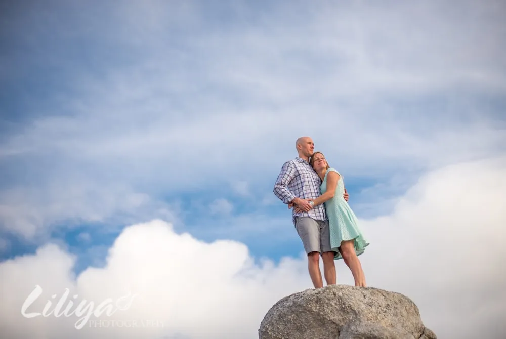 Couple standing on a rock against an open sky