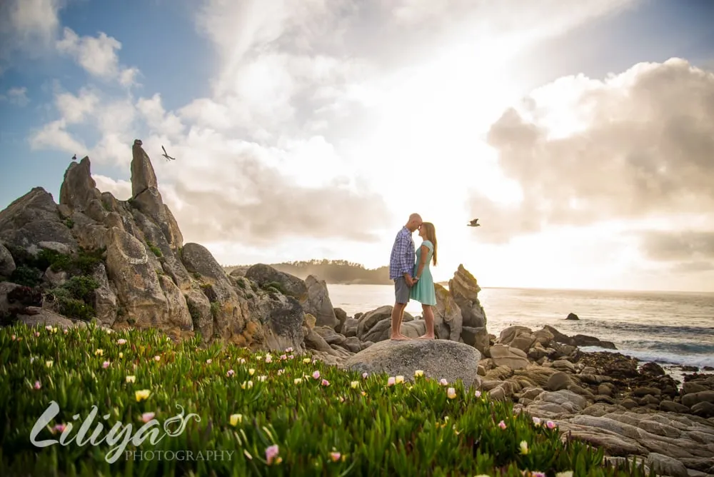 Couple on the rocks above the sea at sunset