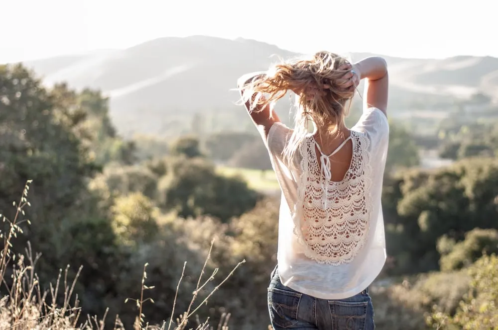 Woman in a field with her arms raised, backlit