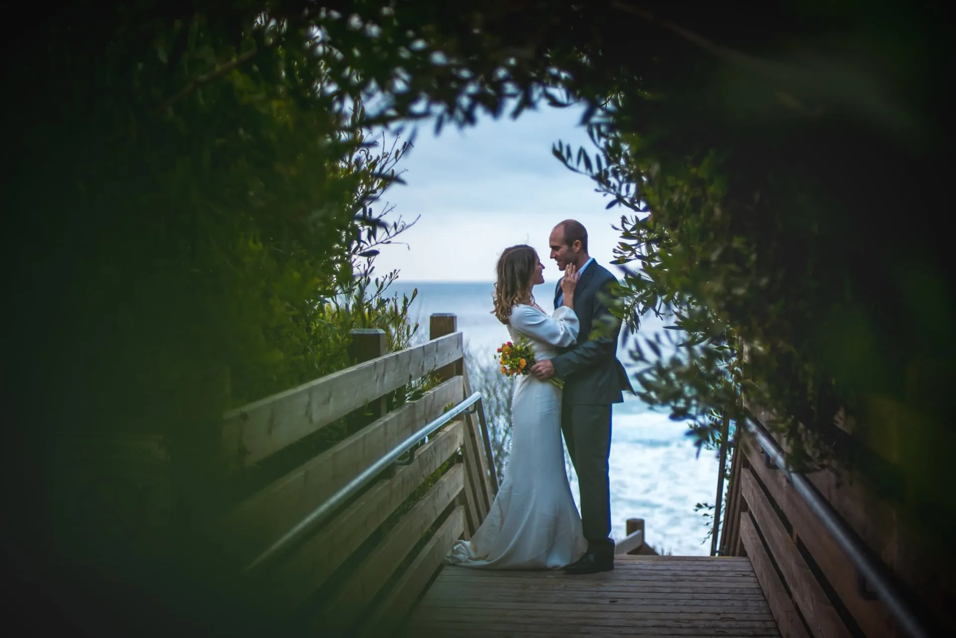 Bride and groom on a wooden walkway above the ocean