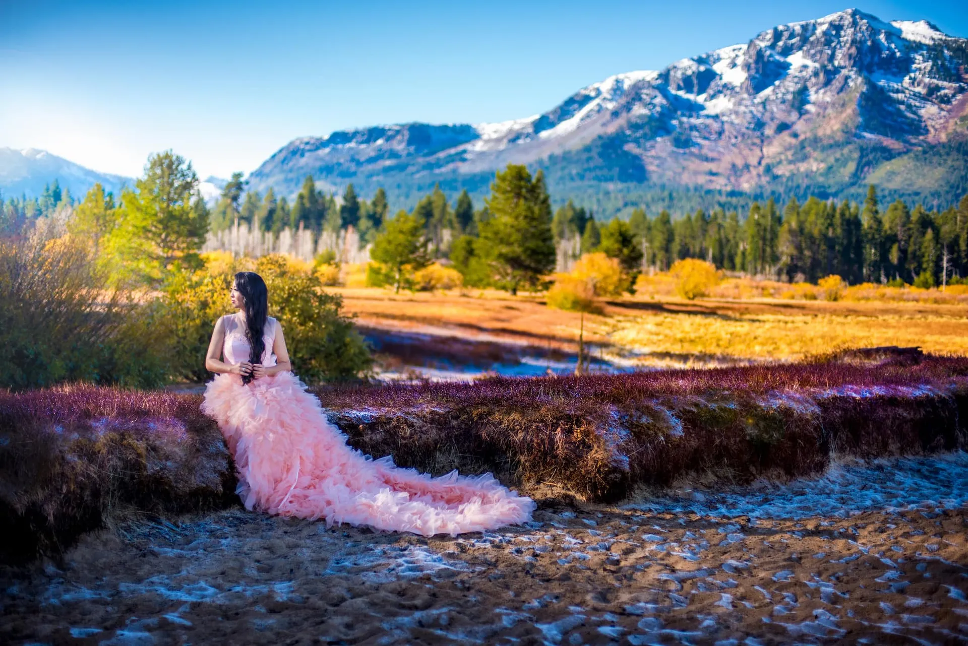 Woman in a pink gown beside a mountain river