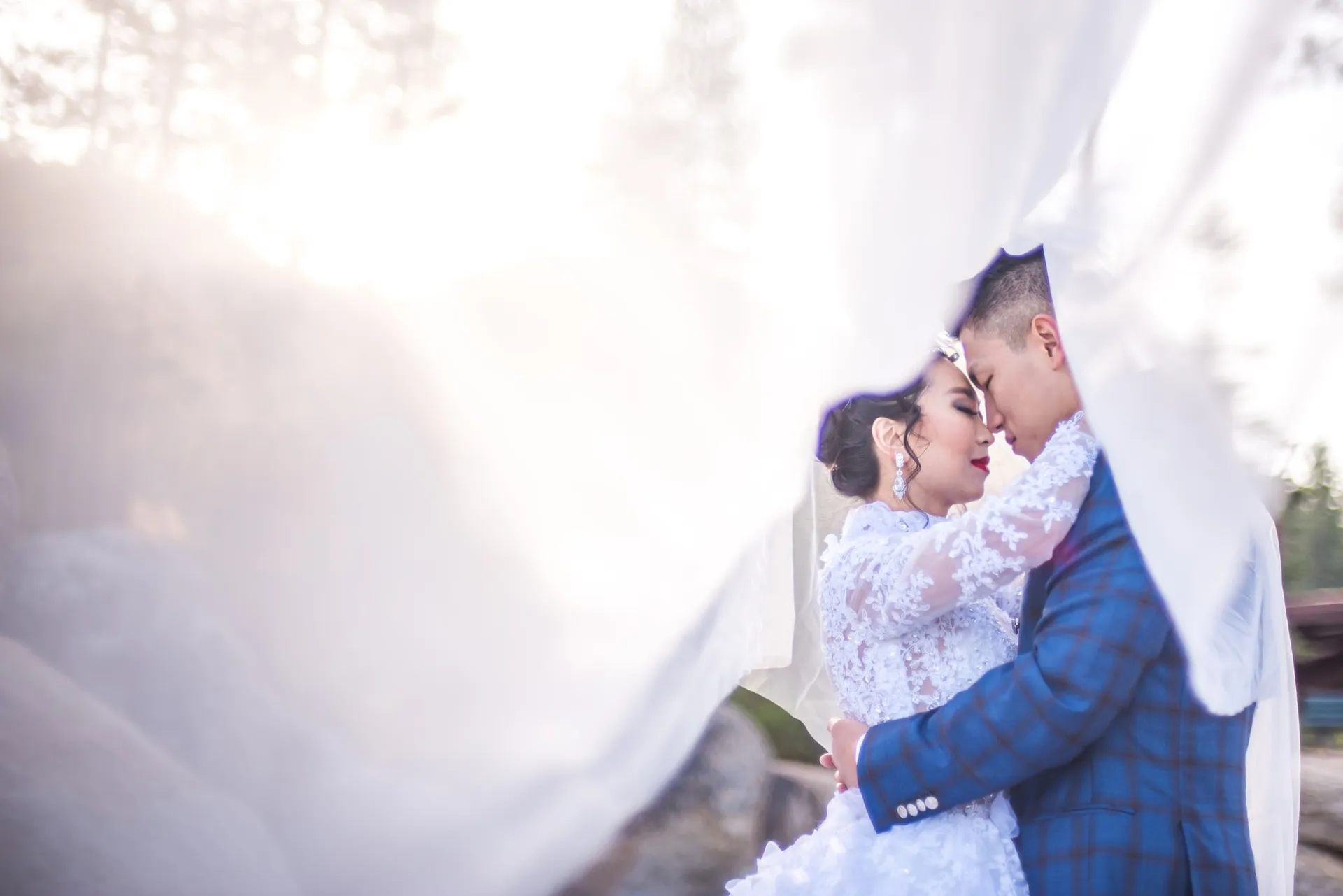 Bride and groom kissing beneath her veil